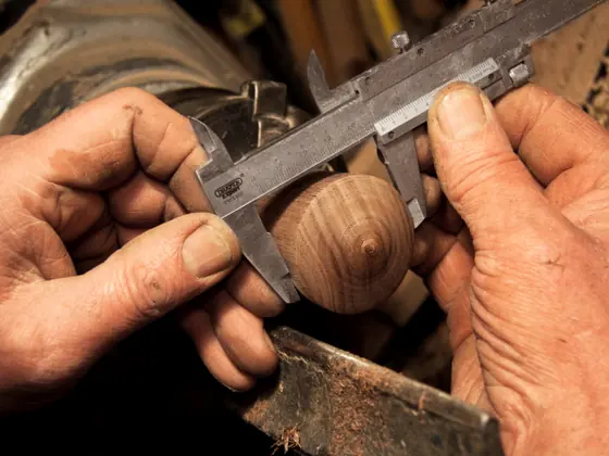 A pair of hands taking a measurement with calipers