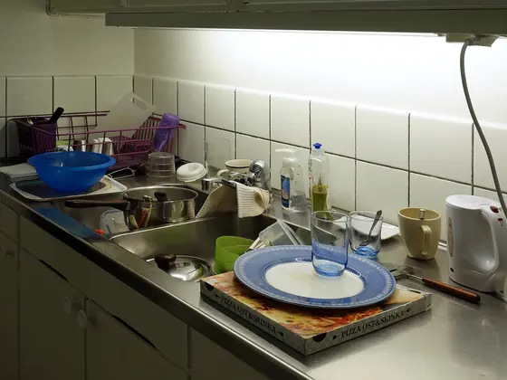 A kitchen sink piled with dishes and standing water