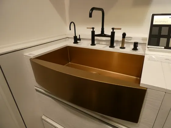 A hammered copper farmhouse sink set into a light counter