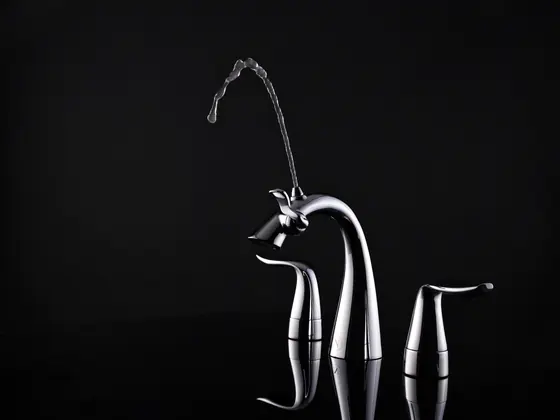 A sculptural widespread basin faucet photographed against black