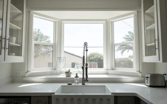A farmhouse sink under a bay window in a country kitchen