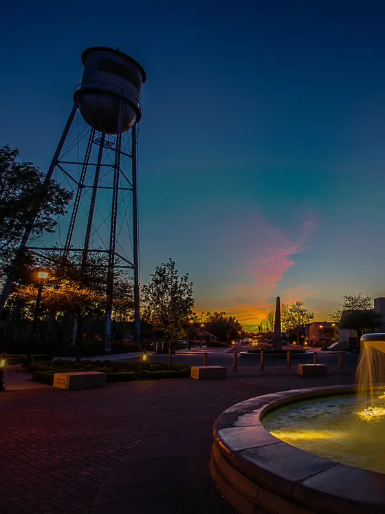 The Tracy water tower lit at dusk above the downtown fountain