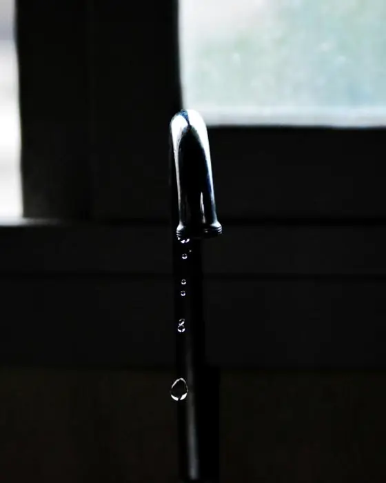 A faucet dripping in a darkened room