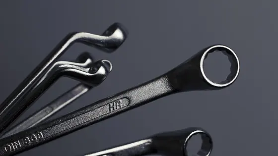Combination wrenches laid out on a dark bench