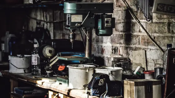 A working bench with tools and parts laid out under lamplight