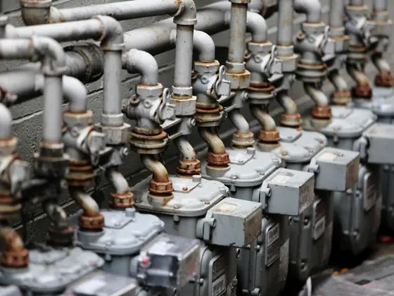 A row of residential gas meters and shutoff valves